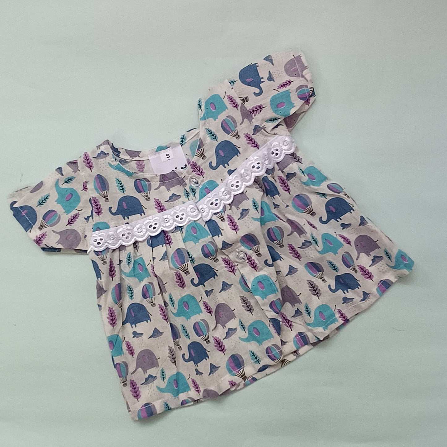 Baby dress with elephant pattern on a light gray background

